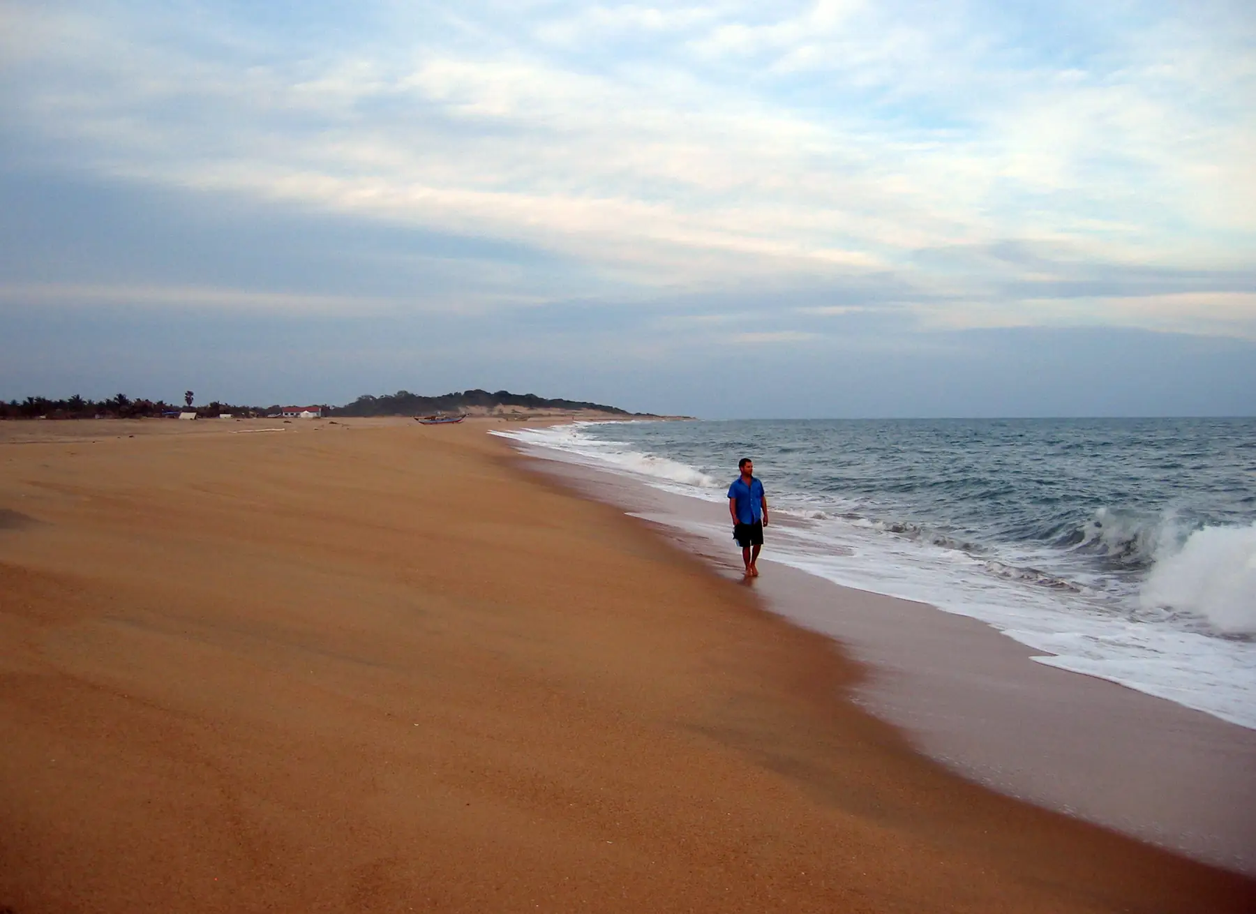 Waves rolling onto the long sandy beach south of Arugam Point, a person walking along the shoreline.