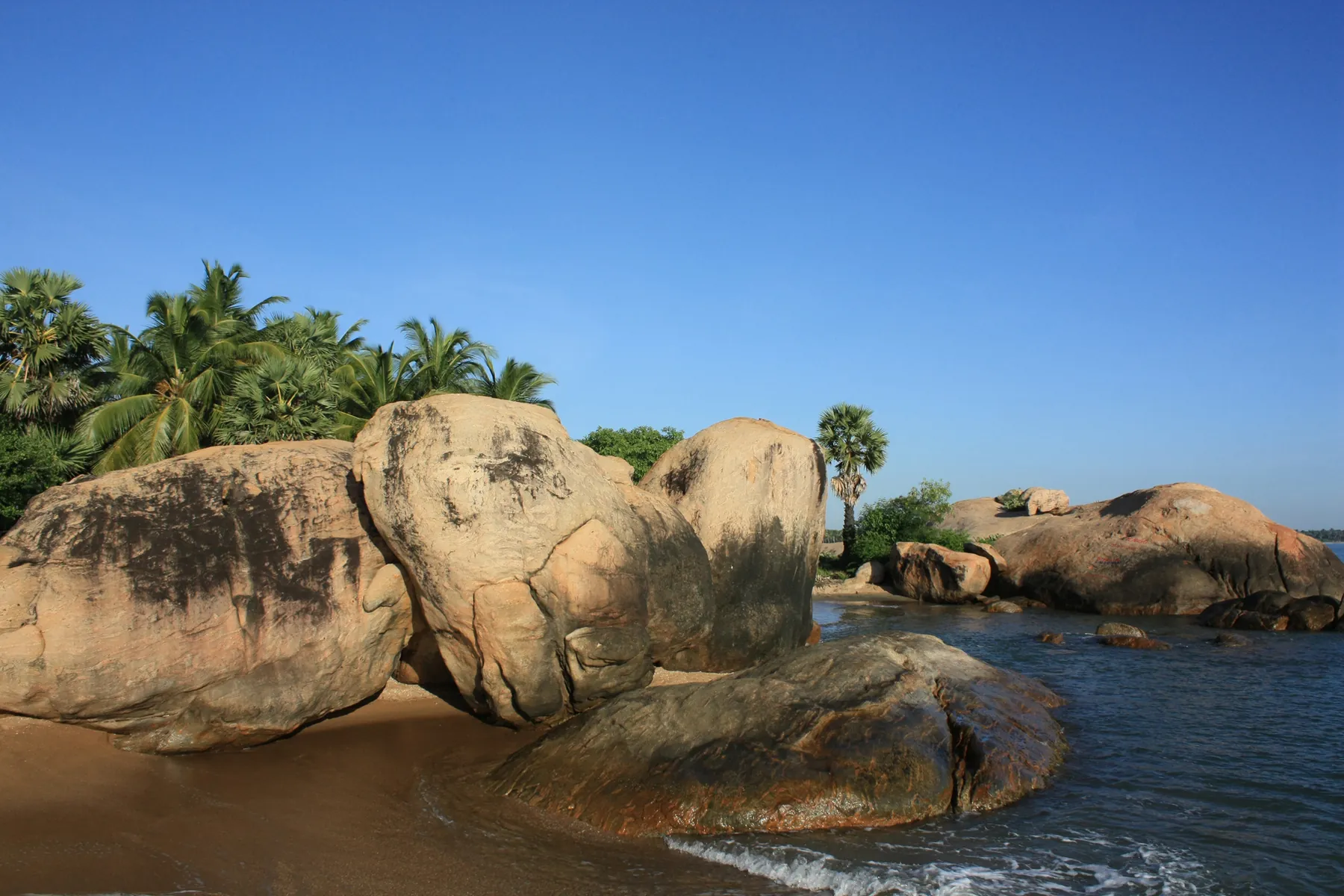 Large granite boulders at the water's edge on Pasikudah beach.