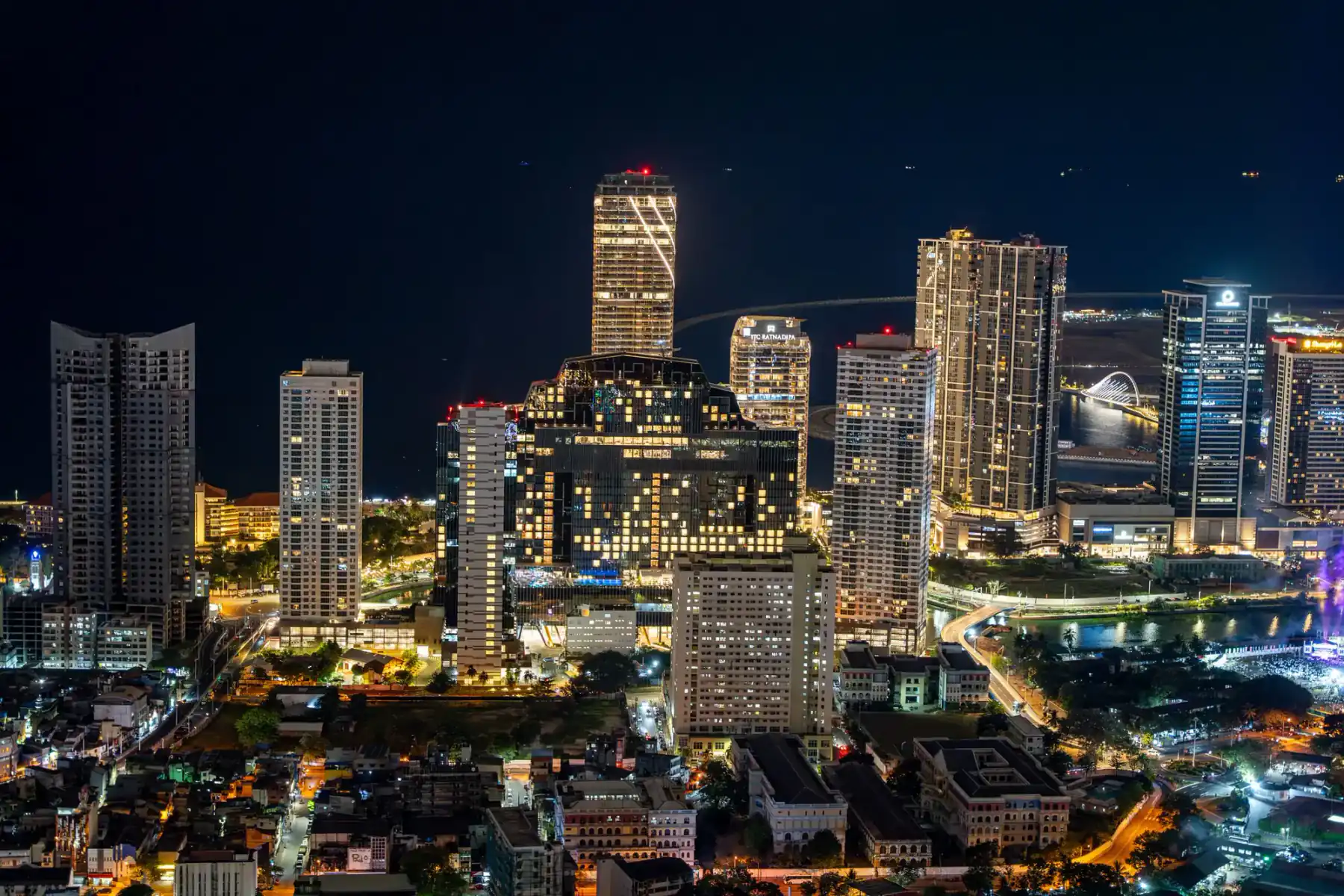 Colombo's high-rise skyline lit up at night, the illuminated ITC Ratnadipa tower at its centre.