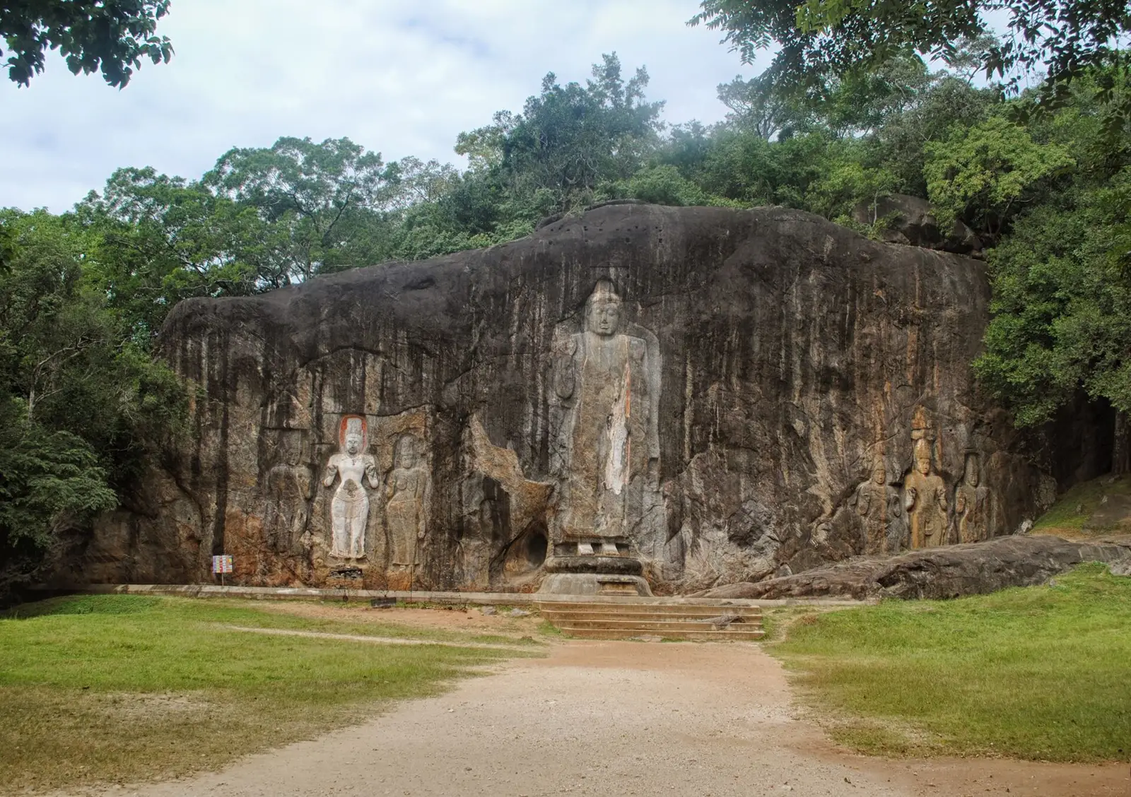A tall standing Buddha and smaller figures carved in relief into the rock face at Buduruwagala near Wellawaya.