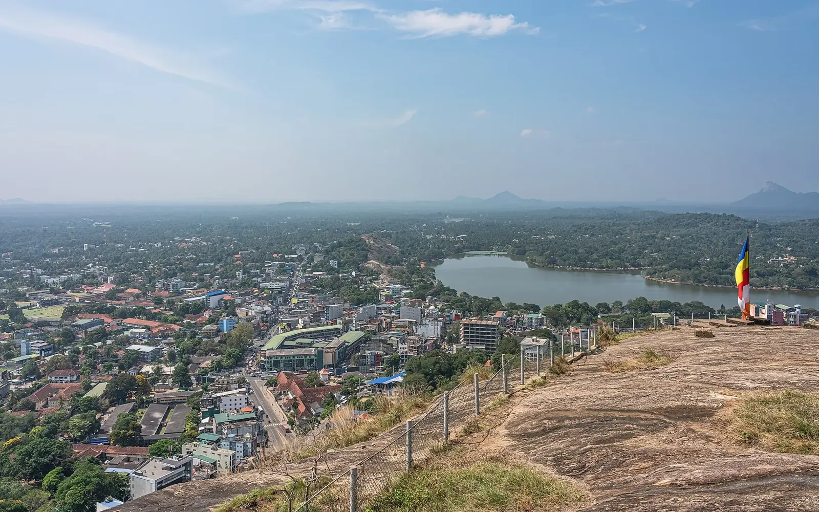 The view from Athugala rock over the roofs of Kurunegala town and Kurunegala Lake, with green hills beyond.