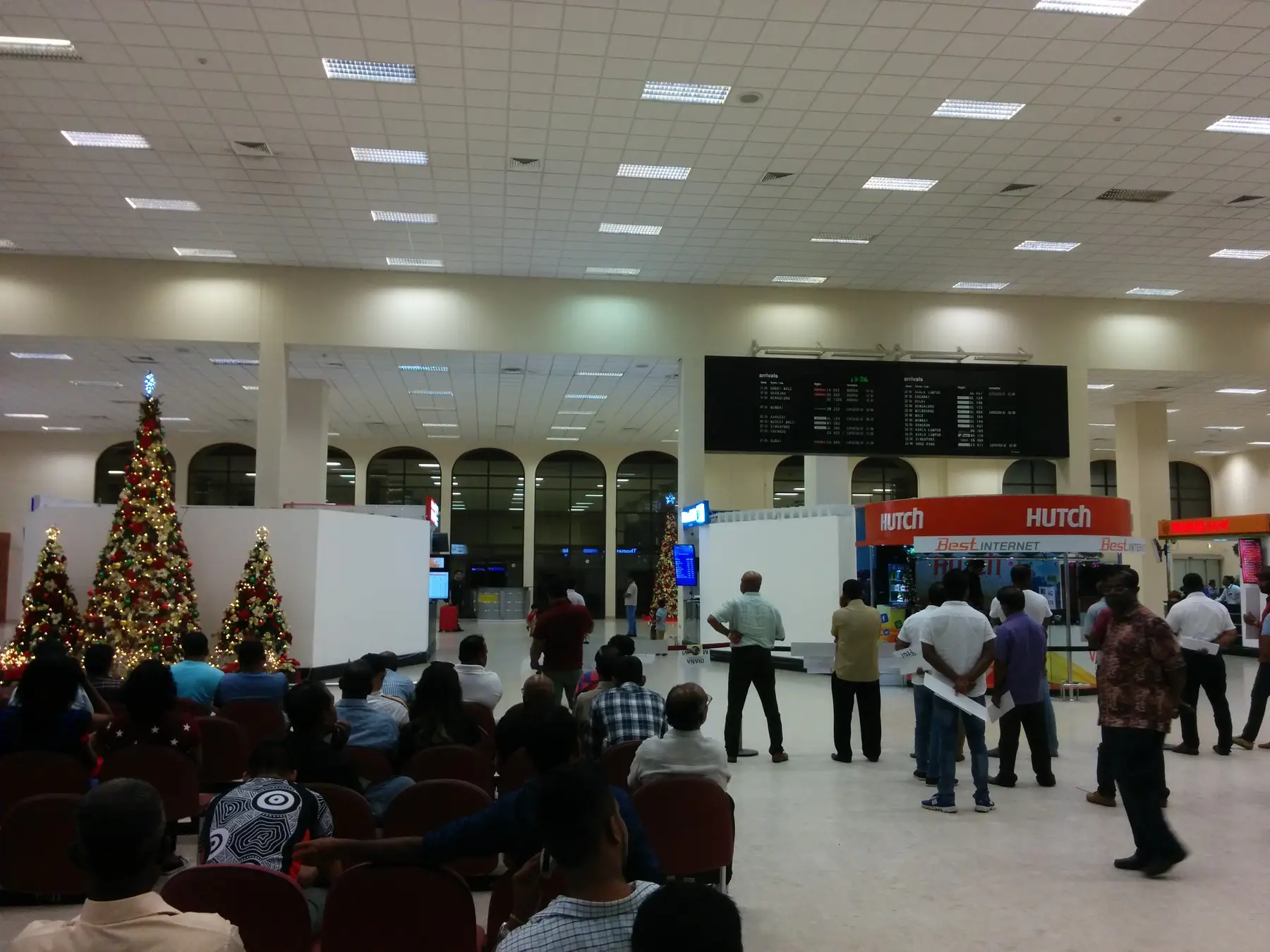 The arrivals hall at Colombo's Bandaranaike International Airport, with a mobile SIM counter and arrivals board.