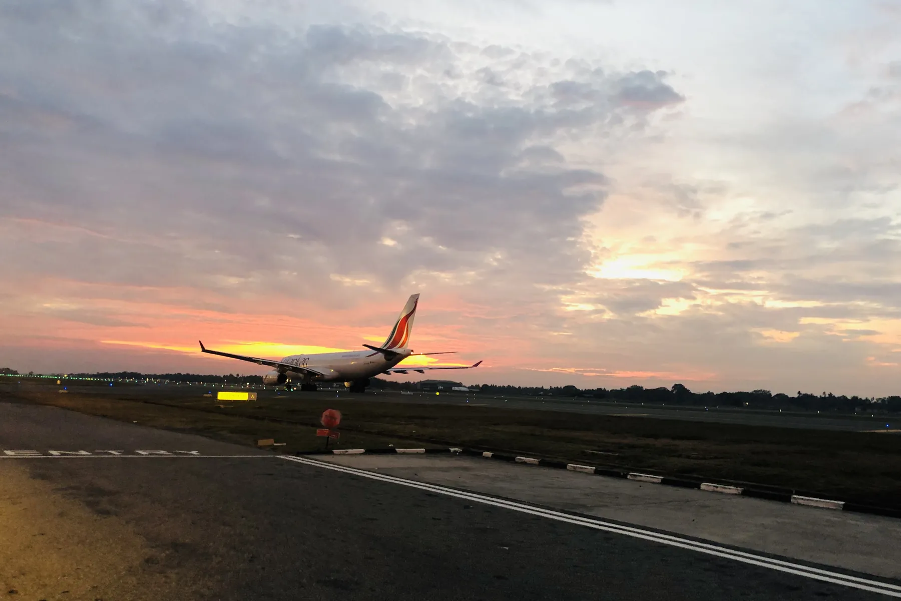 A passenger jet on the runway at Colombo's Bandaranaike International Airport at sunset.