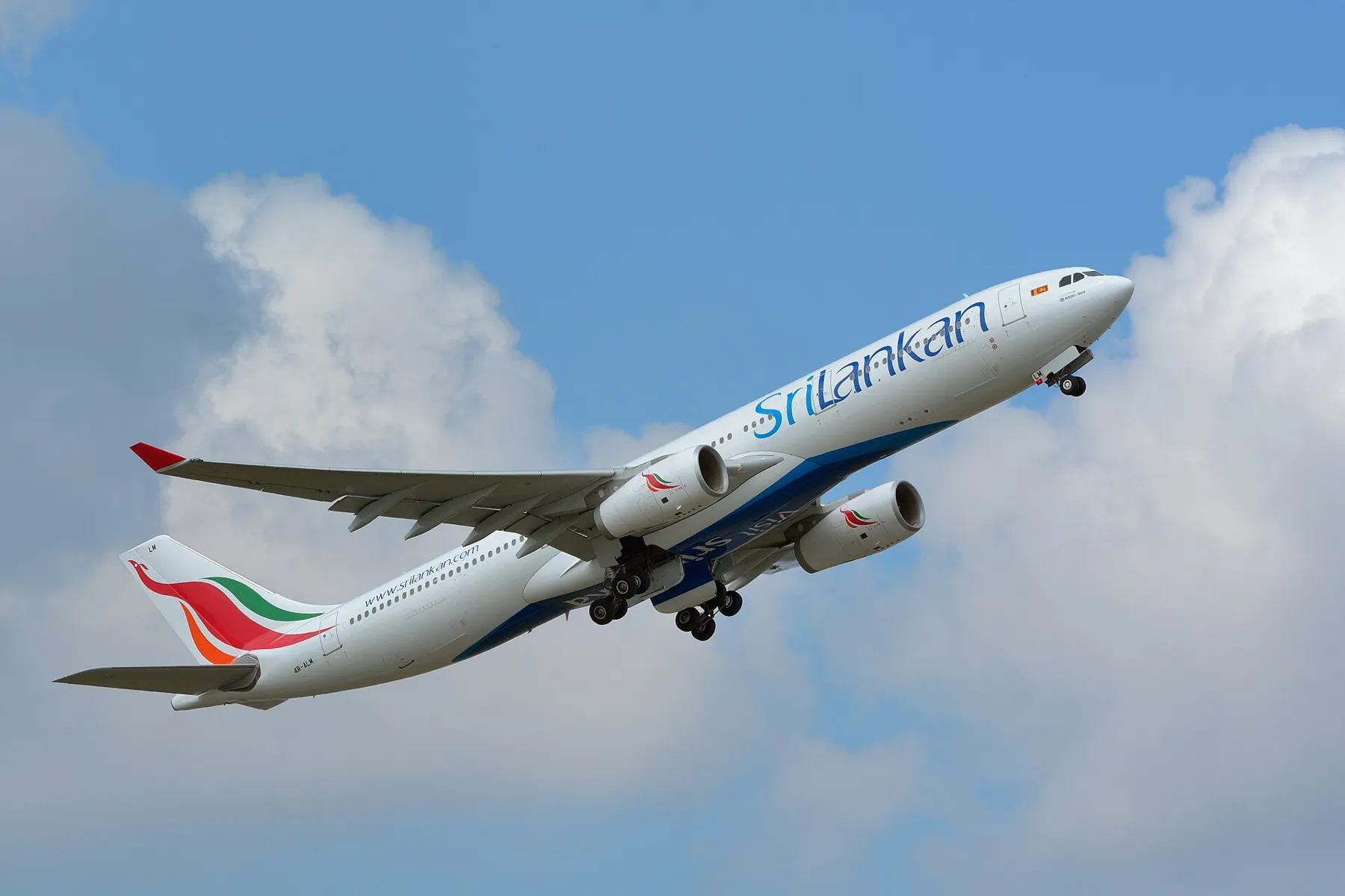 A SriLankan Airlines Airbus A330 climbing into a blue sky with white clouds after take-off.